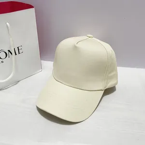 Detail of a minimalist 5-panel cotton baseball cap in creamy white with copper buckle