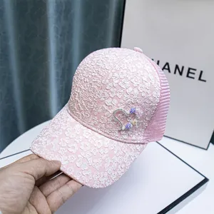Detailed view of pink mesh baseball cap with lace flowers and rhinestone heart decoration