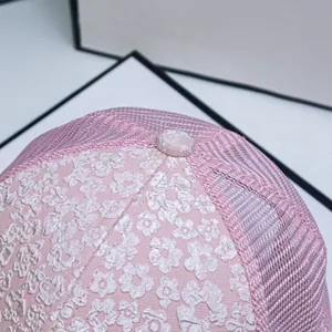 Close-up of pink baseball cap featuring white floral embroidery and breathable mesh
