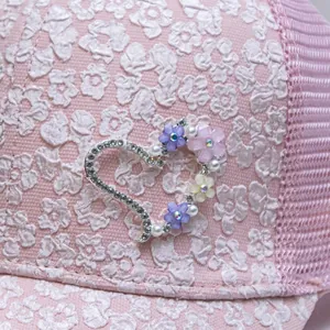 Macro shot of pink baseball cap with rhinestone heart and delicate floral embroidery