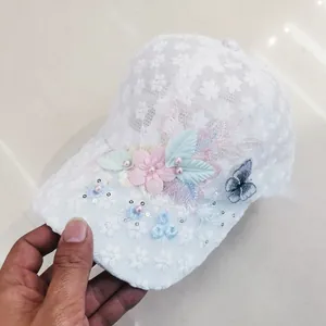 Dettaglio cappello in pizzo bianco con fiori 3D, perle e ricamo di farfalla blu