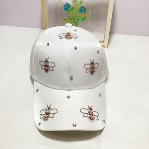 Detail of white satin baseball cap with sparkling rhinestone bee motifs and crystal studs