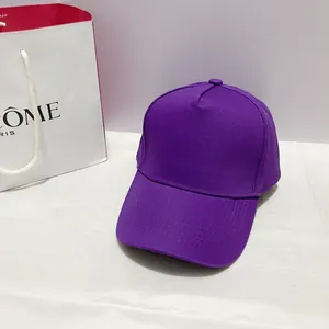 Detail of dark purple 5-panel cotton baseball cap with copper buckle on a minimal background