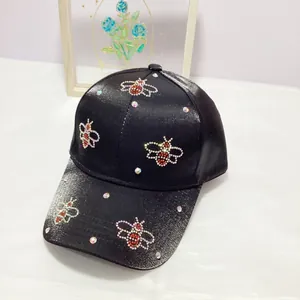 Detail of black satin baseball cap featuring beaded honeybee motifs and rhinestones