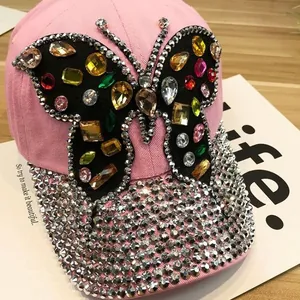Détail d'une casquette rose avec papillon en strass colorés et visière ornée de cristaux