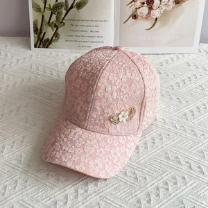 Detailed view of pink floral jacquard baseball cap with rhinestone heart and pearl flower