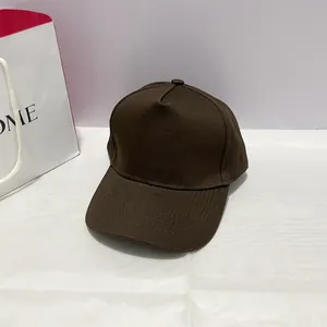 Detailed close-up of dark brown five-panel cotton baseball cap with adjustable copper buckle