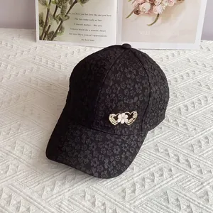 Detail of black baseball cap featuring 3D floral texture and metallic heart ornaments