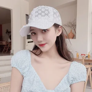 Close-up of white lace baseball cap with floral embroidery and pearl embellishments