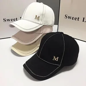 Détail de quatre casquettes de baseball avec logos M et coutures ornés de strass