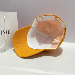 Detail view of bright orange cotton baseball cap interior with wash label and metal buckle