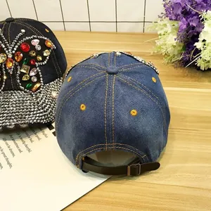 Détail de casquettes en denim avec strass papillon et lanière de réglage en cuir