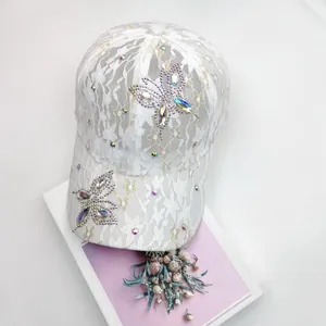 Detailaufnahme einer weißen Spitzen-Baseballkappe mit glitzernden Schmetterlingsmotiven