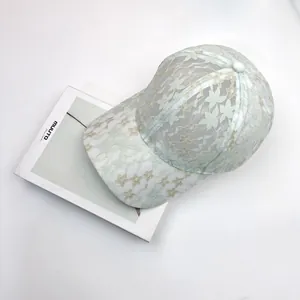 Close-up of light green lace baseball cap featuring intricate floral embroidery and mesh