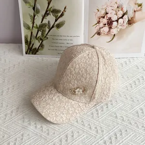 Close-up of beige lace baseball cap featuring floral texture and a heart diamond brooch