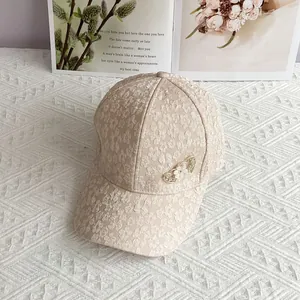 Detail of beige baseball cap featuring white flower lace and heart-shaped brooch decor