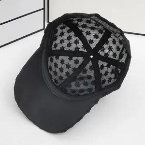 Close-up of black lace baseball cap showing intricate floral cutout patterns and mesh