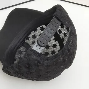 Close-up of black lace baseball cap featuring floral patterns and adjustable snapback closure