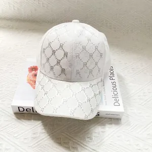 Close-up of a white sun visor cap with rhinestone 'R' patterns and a curved brim
