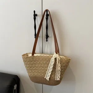 Große Strandtasche aus Stroh mit Lederriemen und Spitzenschleife für den Sommerurlaub