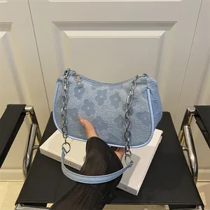 Light blue arc-shaped baguette bag featuring textured floral pattern and silver chain strap