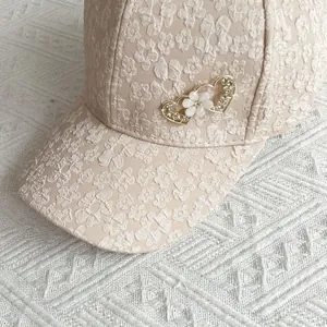 Close-up of floral texture on pink baseball cap with heart rhinestone and pearl metal buckle