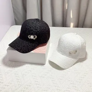 Detail of floral lace baseball caps in black and white with double heart rhinestone buckle
