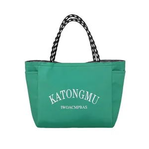 Green canvas tote bag with contrast woven handles and large letter prints on front