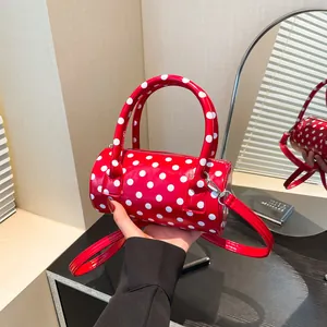 Red boston bag with white polka dots featuring top handles and a detachable shoulder strap