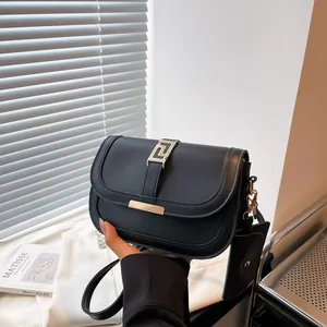 Schwarze Satteltasche aus Kunstleder mit Goldschnalle und kleinem runden Anhänger