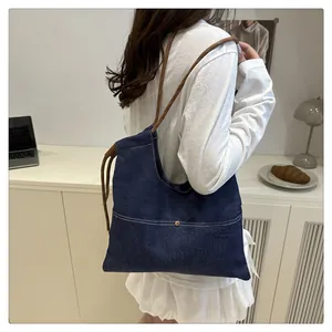 Detail of dark blue denim tote bag with contrast stitching and brown rope handle