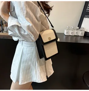 Détail d'un mini sac bandoulière minimaliste en cuir noir et toile porté par le mannequin