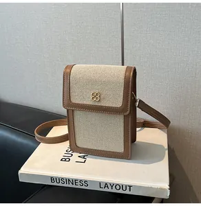 Détail du mini sac de téléphone en toile avec bordure en cuir brun et fermoir trèfle
