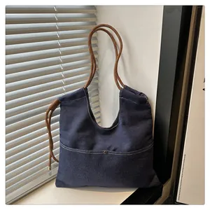 Detail view of large dark blue denim tote bag with durable dark brown braided rope straps