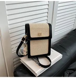 Détail du mini sac bandoulière contrasté avec fermoir fleur dorée et breloque perle