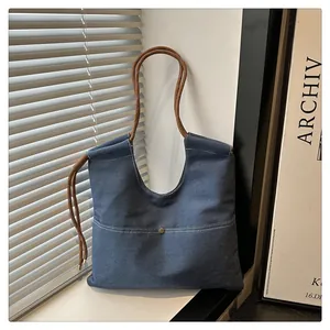 Detail of blue denim tote bag with brown woven rope handles and front pocket