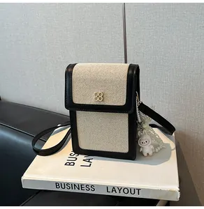 Détail du mini sac de téléphone en toile avec bordure en cuir noir et fermoir doré