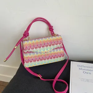 Rainbow woven straw handbag with colorful wave patterns and a fuchsia shoulder strap