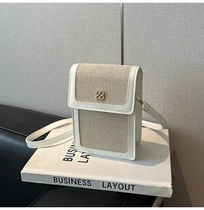 Détail d'un mini sac à téléphone en cuir avec panneaux tissés et boucle fleurie dorée