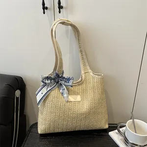 Summer woven beach tote bag with leather straps and floral scarf on a wooden table
