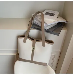 Detail of elegant contrast stitching and gold metal twist lock on the large tote bag