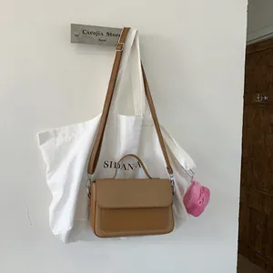 Brown leather and woven crossbody handbag with handle and pink plush charm hanging