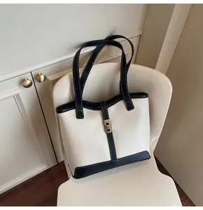 Detail of a contrast color tote bag with gold buckle on a chair in a cozy room