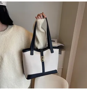 Detail of color-block tote bag with gold twist lock and contrast white stitching