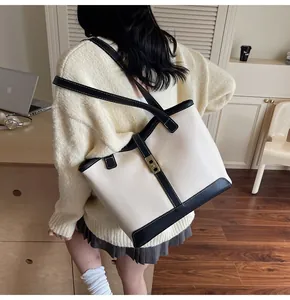 Detail of contrast tote bag featuring a gold square buckle and leather shoulder strap