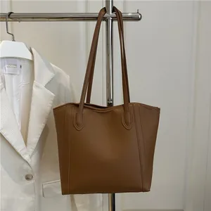 Minimalist brown leather tote bag for women with dual shoulder straps in urban office setting