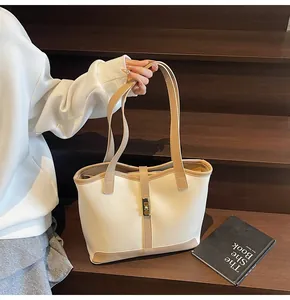 Detail of color-block tote bag with metallic lock closure on wooden stairs