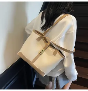Detail of minimalist cream tote bag with khaki straps and gold twist lock on shoulder