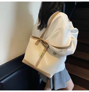 Close-up of contrast trim tote bag with gold metal buckle on a model in a stairwell