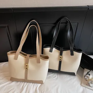 Minimalist color-block tote bag with gold lock and long straps for stylish urban commuting